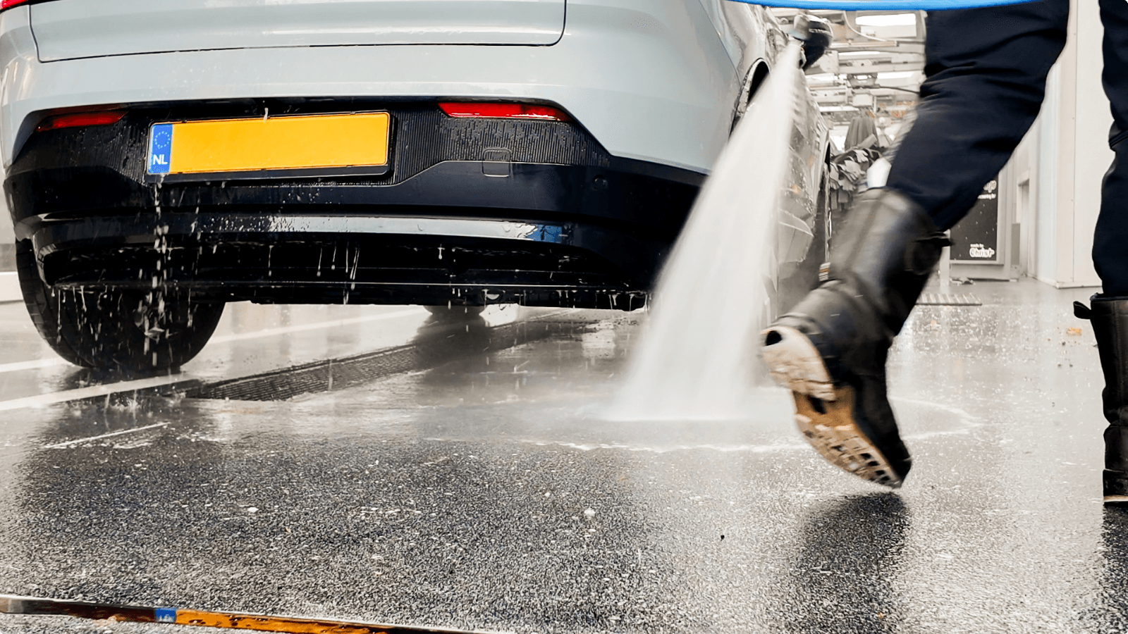 Medewerker van TipTop Carwash spuit water op de Duraquartz Torffelvloer tijdens het wasproces