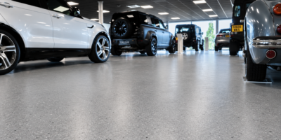 Grote gestorte vloer in showroom met Range Rover, Defender en klassieke Jaguar