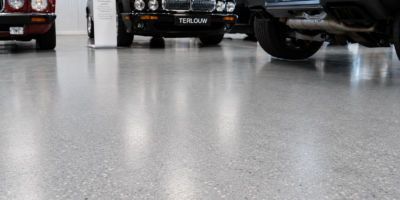 Gepolijste gestorte vloer met lichtreflectie tussen klassieke Jaguar XJ en andere voertuigen