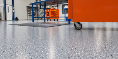 Gietvloer in technische werkplaats Gietvloer in werkplaats met oranje gereedschapskast en blauwe stellage