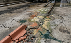 Slijtage en scheurvorming in de betonvloer Gebarsten en aangetaste betonvloer met een afgebroken stuk trottoirband en gekleurde chemische aanslag