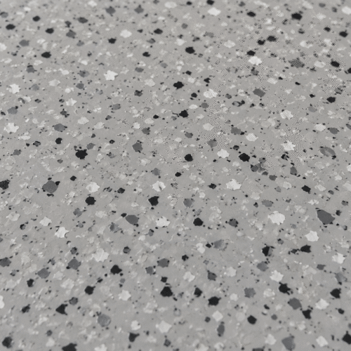 Close-up van een lichtgrijze DuraQuartz coating met witte, grijze en zwarte flakes.