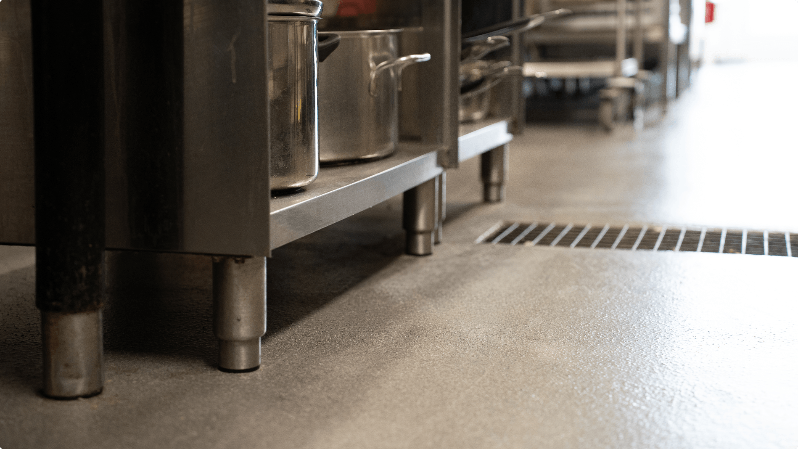 Lichte DuraQuartz troffelvloer met afvoergoot onder RVS werkbanken in de horecakeuken van De Betteld