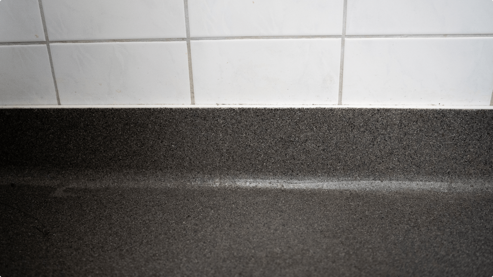 Doorlopende DuraQuartz plint in Mix 876 tegen witte wandtegels in het sanitair van Camping De Betteld