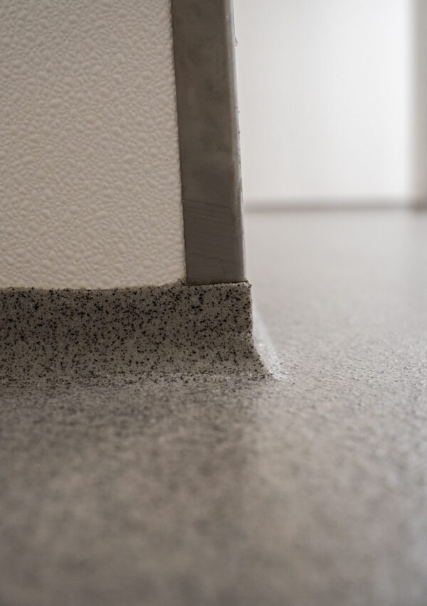 Hygiënische plintafwerking gietvloer Detail van opgezette plint bij gietvloer, naadloze overgang tussen vloer en wand