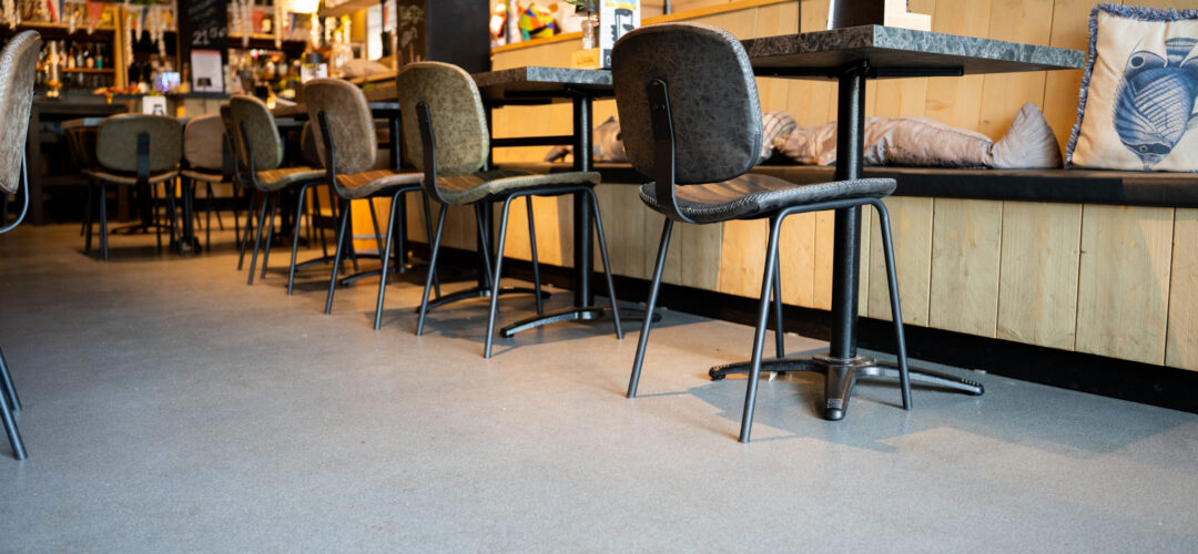 Grijze troffelvloer in een restaurant met houten zithoek en visdecoratie