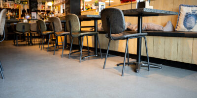 Troffelvloer restaurant Grijze troffelvloer in een restaurant met houten zithoek en visdecoratie