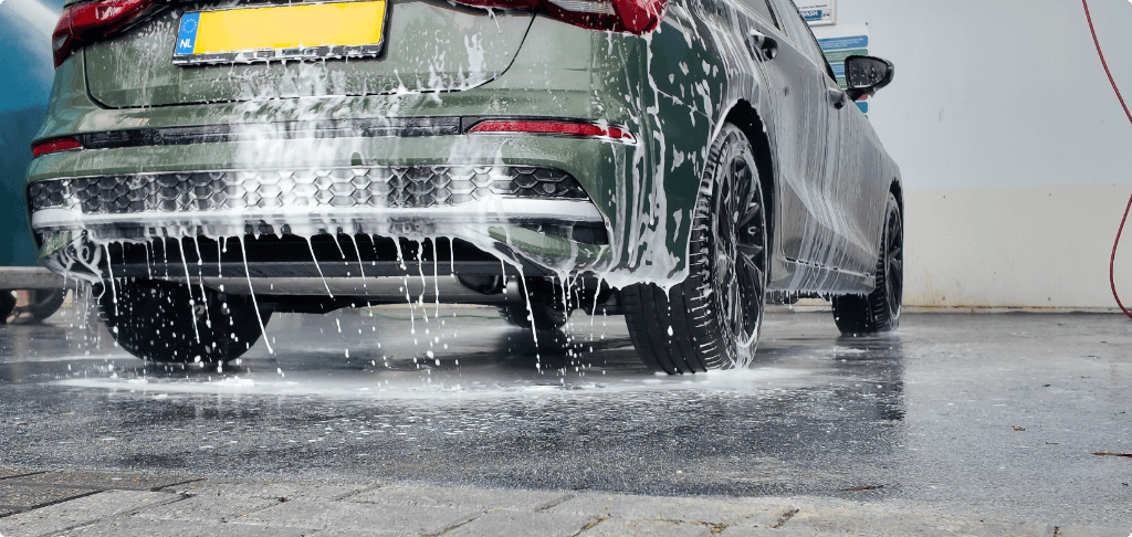 Auto met schuim wordt gewassen in een wasbox met waterafvoer op de vloer