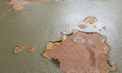 Loslatende coating op vloer in sanitaire ruimte Groenige vloercoating in sanitaire ruimte die op meerdere plekken loslaat en de terracotta ondergrond blootlegt