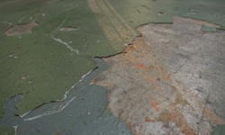 Loslatende coating met bandensporen in werkplaats Groene vloercoating in werkplaats die grootschalig loslaat, met zichtbare bandensporen en roestbruine verkleuring
