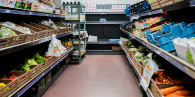 Praktijkbeeld van een goed gevulde koelcel met groente en fruit Roze gespikkelde vloer in koelcel met gangpad tussen schappen vol groente, fruit en zuivel