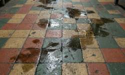 Gladde olievlekken op geblokte werkplaatsvloer Rood, geel en groen geblokte tegelvloer in werkplaats met een spoor van gladde olie en vetvlekke