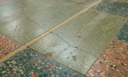 Scheuren in decoratieve terrazzovloer van werkplaats Groene, rode en blauwe terrazzotegels in een geblokt patroon met een gescheurde tegel in het midden