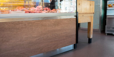 DuraQuartz vloer in slagerij bij vitrine met vleeswaren en houten hakblok.